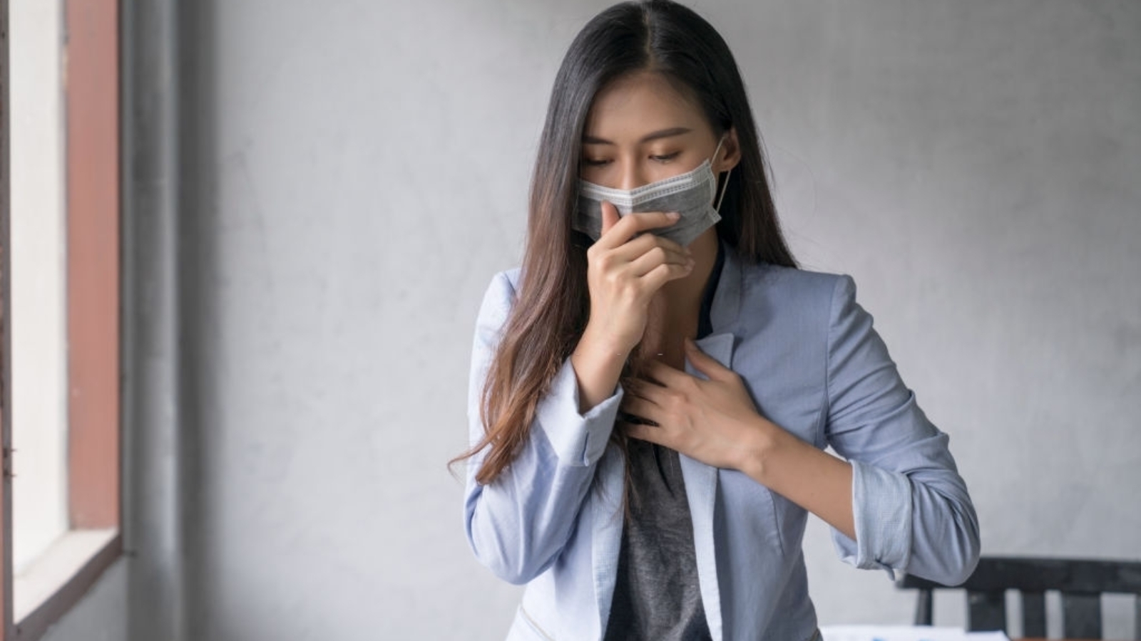 Business woman wearing face mask and cough influenza while working in office