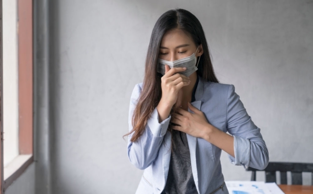 Business woman wearing face mask and cough influenza while working in office
